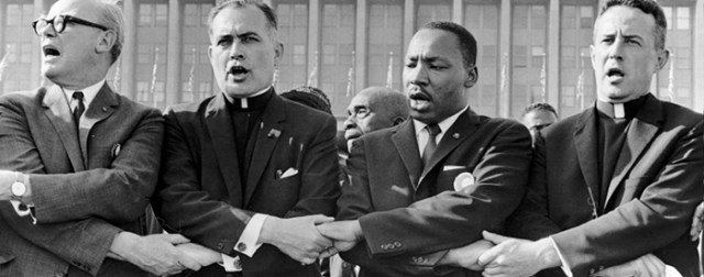 Martin Luther King, Jr. joining hands with Catholic clergy and other religious leaders.